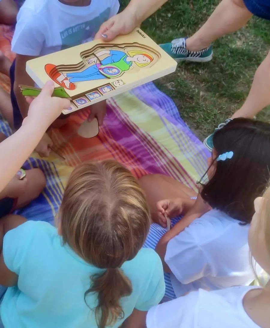 Bambini seduti su una coperta osservano un puzzle in legno sulla gravidanza